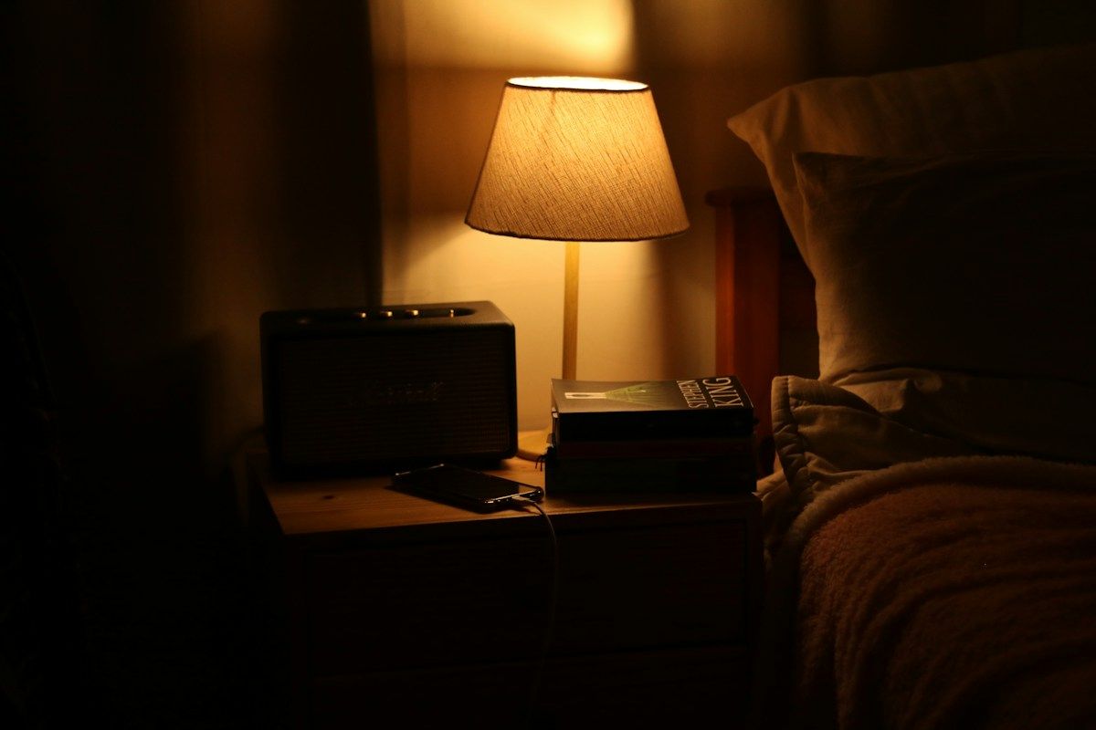 Lampe de chevet allumée dans une chambre plongée dans la pénombre