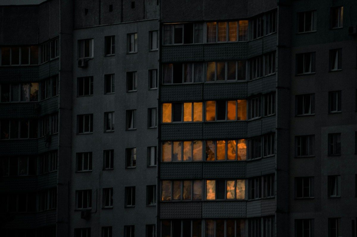 Façade d'immeuble la nuit, quelques fenêtres encore éclairées