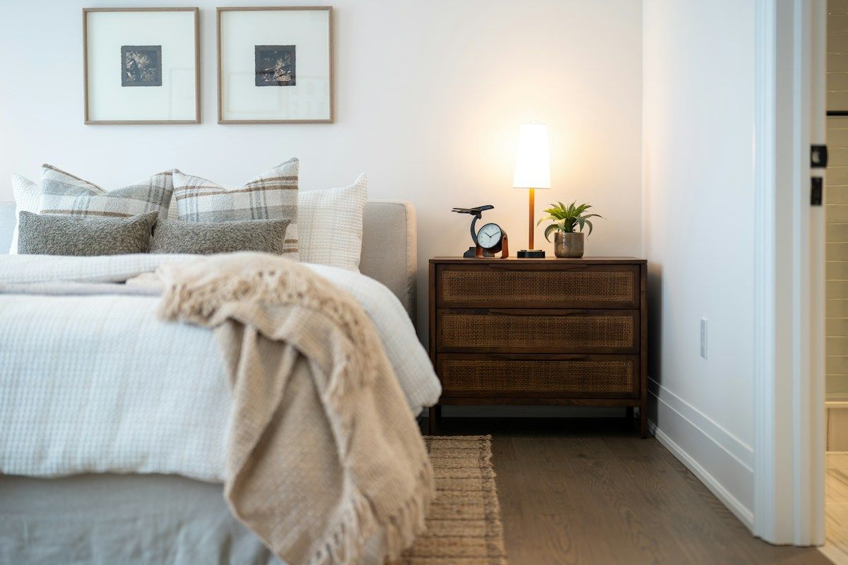 Lit fait avec un plaid et une lampe de chevet allumée dans une chambre claire