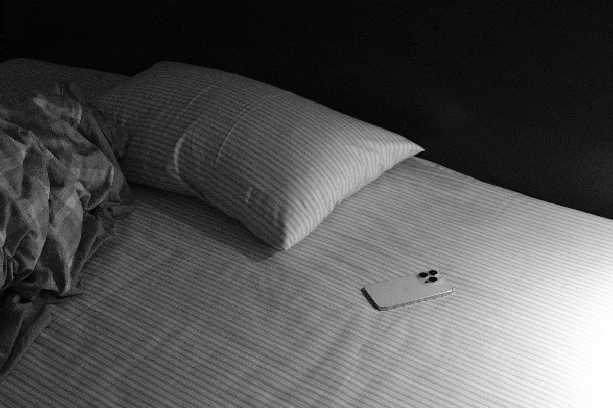 Téléphone posé sur un lit aux draps rayés