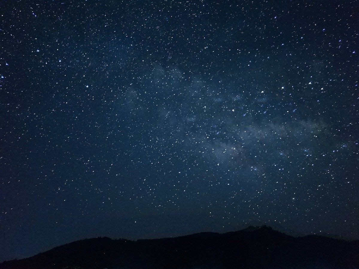 Ciel nocturne étoilé au-dessus d'une ligne de collines